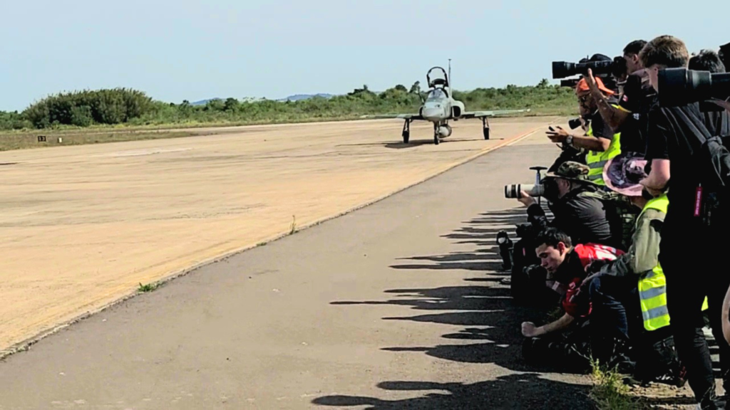 Equipes de imprensa e spotters posicionados na pista da Base Aérea de Canoas durante a Expoaer 2025, registrando um caça F-5M antes de desafio com uma Lamborghini. Foto Gislene Bastos